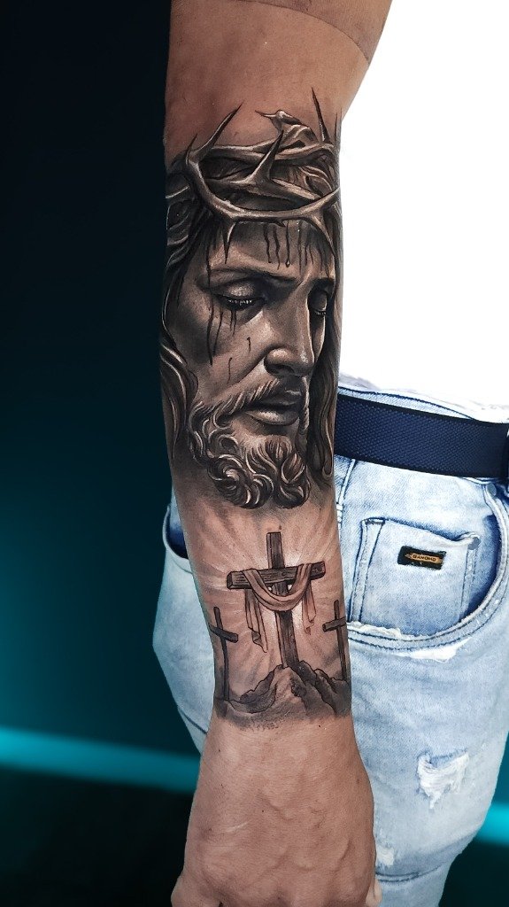 Tatuaje en sombras de Jesús con corona de espinas en el antebrazo